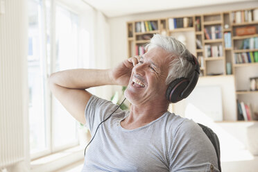 Porträt eines entspannten Mannes, der zu Hause mit Kopfhörern Musik hört - RBF003802