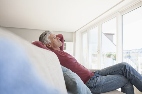 Nachdenklicher Mann sitzt zu Hause auf der Couch - RBF003806