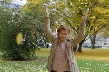 Portrait of smiling girl throwing autumn leaves in the air - LBF001330
