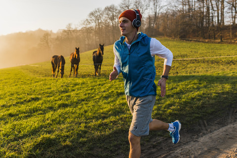 Young man jogging in the morning, horses in the background stock photo