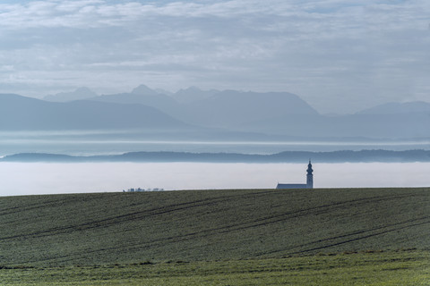Österreich, Ostermiething, Kirche im Nebel, Berge im Hintergrund, lizenzfreies Stockfoto