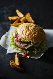 Cheeseburger on greaseproof paper and potato wedges - KSWF001728