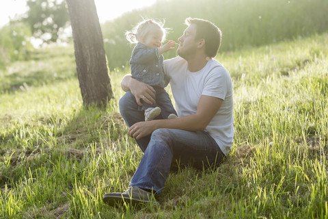 Vater spielt mit seiner kleinen Tochter auf einer Wiese, lizenzfreies Stockfoto