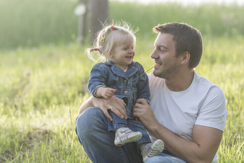 Vater und seine kleine Tochter haben Spaß auf einer Wiese - PAF001516