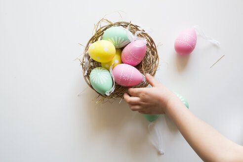 Little girl's hand taking coloured Easter egg - LVF004339