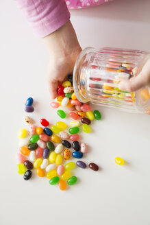 Die Hände eines kleinen Mädchens leeren ein Glas mit Jelly Beans - LVF004346