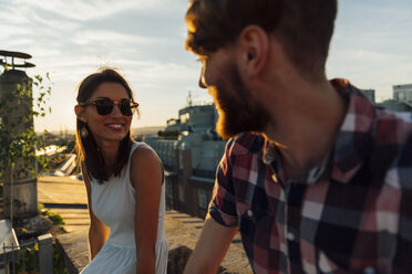 Österreich, Wien, Porträt einer lächelnden jungen Frau mit Sonnenbrille beim Flirten auf einer Dachterrasse - AIF000128