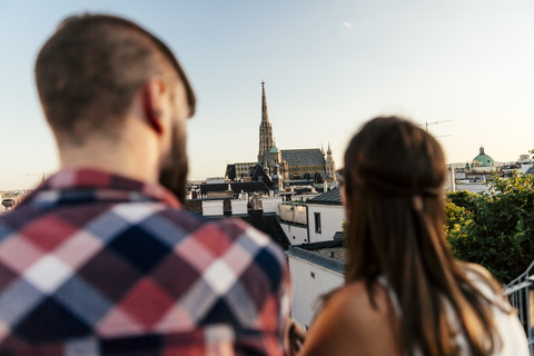 Österreich, Wien, Rückenansicht eines jungen Paares auf der Dachterrasse mit Blick auf den Stephansdom, lizenzfreies Stockfoto