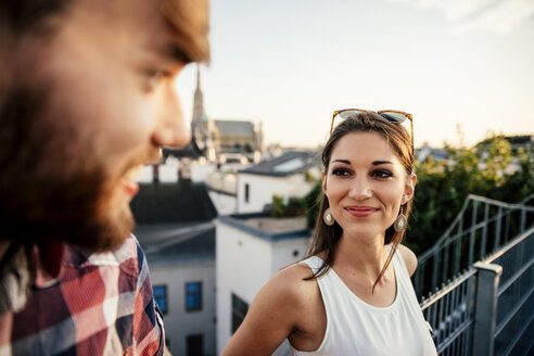 Österreich, Wien, Porträt einer lächelnden jungen Frau, die ihrem Freund auf einer Dachterrasse gegenübersitzt - AIF000133