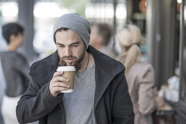 Junger Mann trinkt Kaffee zum Mitnehmen in der Stadt - ZEF007768