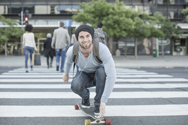 Junger Mann fährt mit dem Skateboard auf einem Zebrastreifen - ZEF007775