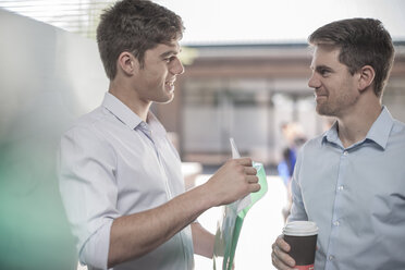 Colleagues talking in the street, holding coffee cups - ZEF007796