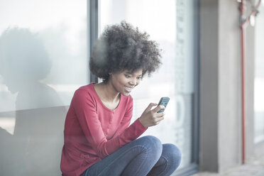 Junge Frau liest Nachrichten auf ihrem Smartphone - ZEF007805