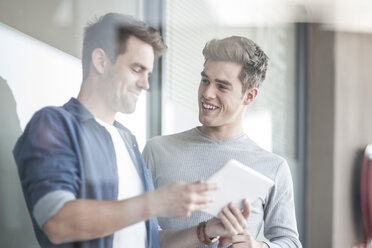 Two young men looking at digital tablet, discussing - ZEF007806