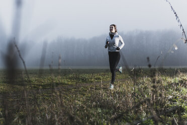 Young woman jogging in nature at a hazy day - UUF006269