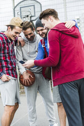 Junge Basketballspieler mit lachendem Smartphone - UUF006284