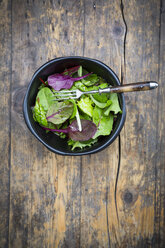 Bowl of organic mixed salad on dark wood - LVF004361