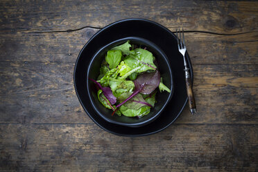 Bowl of organic mixed salad on dark wood - LVF004362