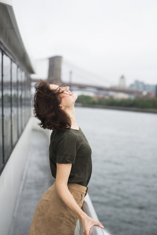 USA, New York City, junge Frau auf einem Ausflugsboot an einem windigen Tag, lizenzfreies Stockfoto
