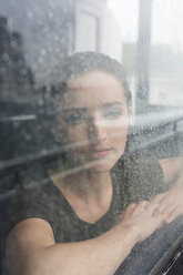 Porträt einer jungen Frau, die an einem regnerischen Tag durch das Fenster eines Ausflugsbootes schaut - GIOF000611