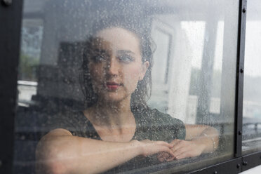 Porträt einer jungen Frau, die an einem regnerischen Tag durch das Fenster eines Ausflugsbootes schaut - GIOF000612