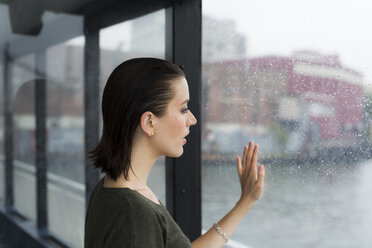 Junge Frau schaut durch das Fenster eines Ausflugsbootes an einem regnerischen Tag - GIOF000617