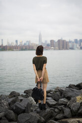 USA, New York City, back view of young woman looking to Manhattan skyline from Williamsburg bank - GIOF000620