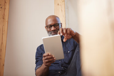 Portrait of smiling man looking at digital tablet - RHF001147