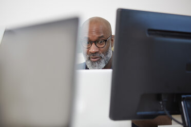 Portrait of astonished man between computer monitors - RHF001163