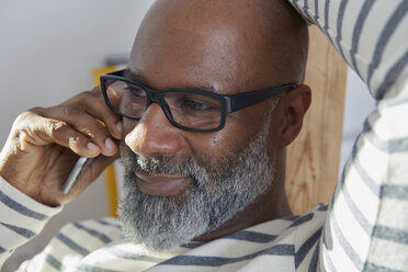 Portrait of bald man with grey beard telephoning with smartphone - RHF001193