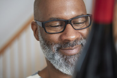 Portrait of smiling man looking at wine bottle - RHF001210