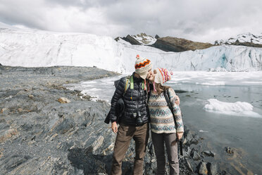 Peru, couple wearing wool chullos and kissing in front of Pastoruri glacier - GEMF000586
