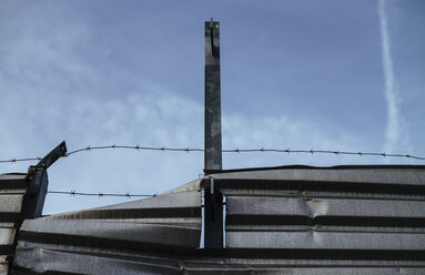 Twisted steel sheet and razor wire in front of sky - DASF000039