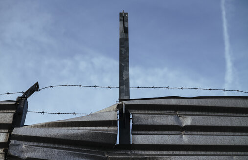 Verdrehtes Stahlblech und Stacheldraht vor dem Himmel - DASF000039