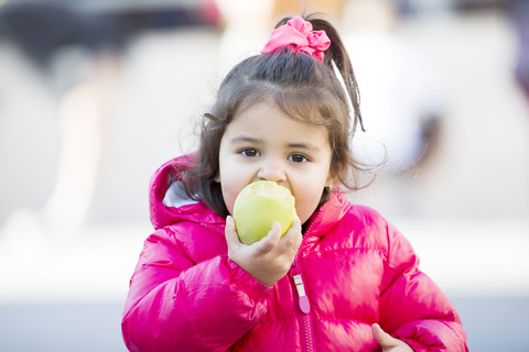 Portrait of little girl eating an apple stock photo