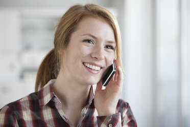 Porträt einer lächelnden jungen Frau, die mit einem Smartphone telefoniert - RBF003838