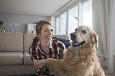 Portrait of smiling young woman holding paw of her dog - RBF003844