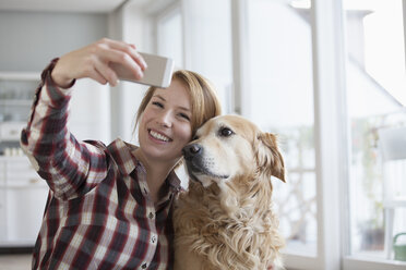 Porträt einer lächelnden jungen Frau, die ein Selfie mit ihrem Hund macht - RBF003847