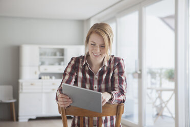 Portrait of smiling young woman using her digital tablet at home - RBF003850