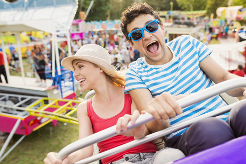 Happy couple at fun fair riding roller coaster stock photo