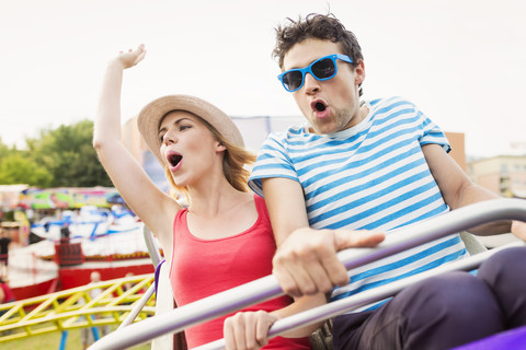 Happy couple at fun fair riding roller coaster stock photo