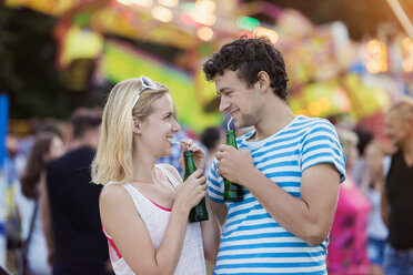 Glückliches Paar auf dem Jahrmarkt beim Trinken von Softdrinks - HAPF000106