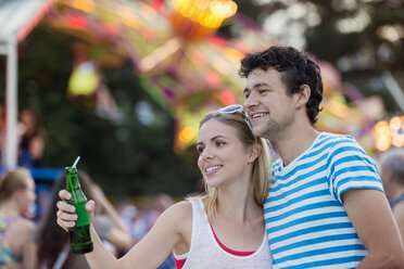 Glückliches Paar auf dem Jahrmarkt, lächelnd und mit Softdrink in der Hand - HAPF000108