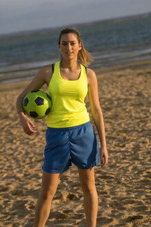 Spanien, Junge Frau spielt Fußball am Strand - KIJF000086