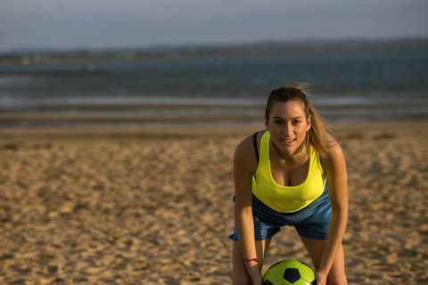 Spanien, Junge Frau spielt Fußball am Strand, lizenzfreies Stockfoto