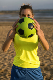 Spanien, Junge Frau spielt Fußball am Strand - KIJF000090