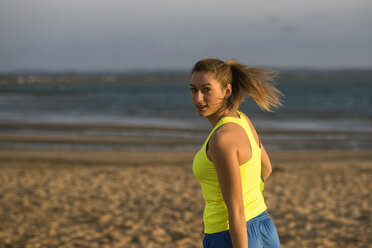 Spanien, Junge Frau spielt Fußball am Strand - KIJF000091