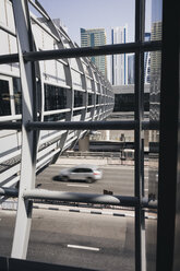 VAE, Dubai, Stadtszene mit Skywalk, fahrendem Auto und Wolkenkratzern im Hintergrund - MAUF000208