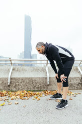 Austria, Vienna, exhausted athlete wearing earphones - AIF000155