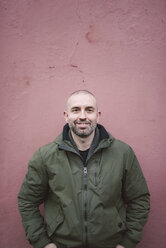 Portrait of smiling bald man standing in front of a wall - RAEF000767
